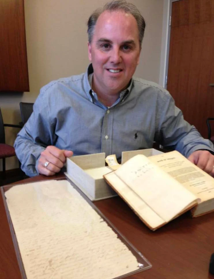 Rick examining an early Book of Mormon and historical materials at a library